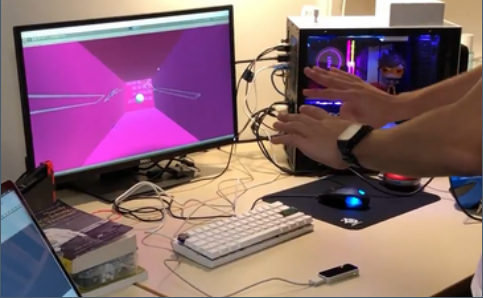 Player's hands over a Leap Motion sensor controlling a pink 3D brick-breaker game